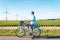 Young man electric green bike bicycle by windmill farm , windmills isolated on a beautiful bright day Netherlands