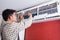 Young man electrician cleaning air conditioning in client house