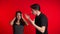Young man emotionally screaming at his wife or girlfriend on red background
