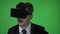 Young man enjoying a great time while using futuristic technology with VR glasses to watch music videos and dance on green screen