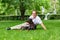 Young man enjoying a sunny day in the park with his dog. dobermann. They are playing together lying on the green grass.