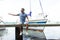 Young Man enjoying time at riverside marina, sitting on pier. young man relax docks at the pier by the harbor