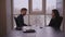 Young man executive interviewing woman sitting at desk on window background in office.