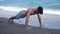 Young man exercising, doing push-ups on beach