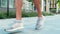 Young man exercising outside. Camera concentrated on male`s legs jogging on street in white sneakers. Exercising or