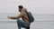 Young man exploring the gray beach after a rain beside of a seashore , closeup capturing video , man taking some wet