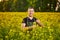 A young man farmer or agronomist examines the quality of rapeseed oil on a rape field. Agribusiness concept