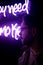 A young man fashionably dressed standing in the street at night. Illuminated signboards, neon, lights.