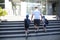 Young man, father leads two children with school bags, hold hands, climb the stairs, Back to school concept