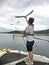 A young man is feeding a seagull with his right hand on a boat in Japan.