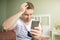 Young man feelling worried while holding phone or smartphone in his hand. One hand in his head