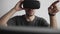 Young man finish using virtual reality goggles headset and sitting in the office against computer and trying to touch