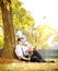 Young man with flowers sitting on grass and checking the time, i