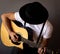 Young man focused playing an acoustic guitar. Grey background. Selective focus. b&w