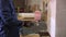 Young man in a furniture factory applies a glue on a wooden piece of the sofa