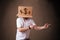 Young man gesturing with a cardboard box on his head with dollar