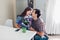 Young man gifting bouquet of flowers to his girlfriend in kitchen. Happy couple hugging. Romantic surprise