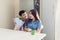 Young man gifting bouquet of flowers to his girlfriend in kitchen. Happy couple hugging. Romantic surprise