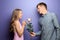 Young man giving beautiful flower to his beloved girlfriend on color background
