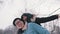 Young man giving piggyback ride to his girlfriend in the park on snowy winter day. Newlywed asian couple having fun