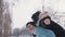 Young man giving piggyback ride to his girlfriend and spinning her in the park on snowy winter day. Newlywed asian