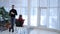 Young man with glasses and a black pullover, talking to a classmate on background of panoramic windows at university.