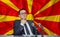 Young man in glasses and a jacket at an international meeting or press conference negotiations, on the background of the flag