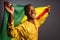 Young man in gold national clothes smiling into the camera and posing with Congo Flag isolated in gray Background.