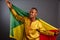 Young man in gold national clothes smiling into the camera and posing with Congo Flag isolated in gray Background.