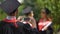 Young man in graduation cap photographing best friends on mobile phone