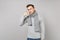 Young man in gray sweater, scarf doing phone gesture like says call me back isolated on grey background. Healthy fashion