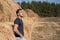 A young man in a gray t-shirt and jeans stands at a haystack, breathing clean air, freshness, rest after work, harvesting, concept