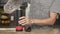 Young man in a gray T-shirt pours water into a glass from a stainless steel thermos or plastic bottle in a beautiful