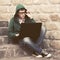 Young man in green hoodie using laptop on the steps