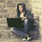 Young man in green hoodie using laptop on the steps