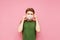 Young man in a green t-shirt holding a gauze medical mask on a pink background, personal protective equipment. Copy space.