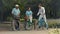 Young man greets senior couple on bicycles in park