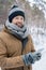 Young man in grey beanie, scarf, gloves warm jacket scrolling in smartphone