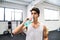 Young man in gym resting in between exercises, drinking water.