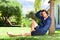 Young man with hand in hair sitting against tree