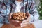 young man hand hold a bowl of almond nut white sited