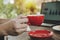 Young man hand holding red coffee cup relaxed and working with digital laptop computer on desk at cafe