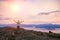 The young man with hands in the air standing on the cliff of rock