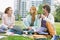 Young man having coffee while studying with female friends at college campus