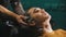 A young man having his hair washed with shampoo in barbershop