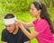 Young man with head injury receiving treatment and bandage around skull from woman, outdoors environment