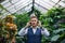 Young man with headphones standing in greenhouse in botanical garden.