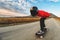 A young man in helmet and a leather suit in a special rack rides a longboard on afsaltu on background mountains and