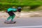 A young man in helmet and a leather suit in a special rack rides a longboard on afsaltu on background mountains and