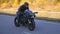 Young man in helmet riding fast on modern sport motorbike at autumnal highway. Motorcyclist racing his motorcycle on